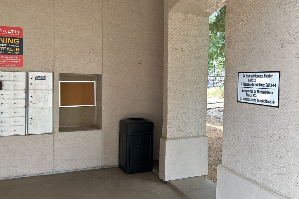 Sign with emergency contact info on wall in mailbox area at an apartment complex