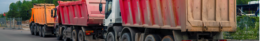 three dump trucks lined up on the street