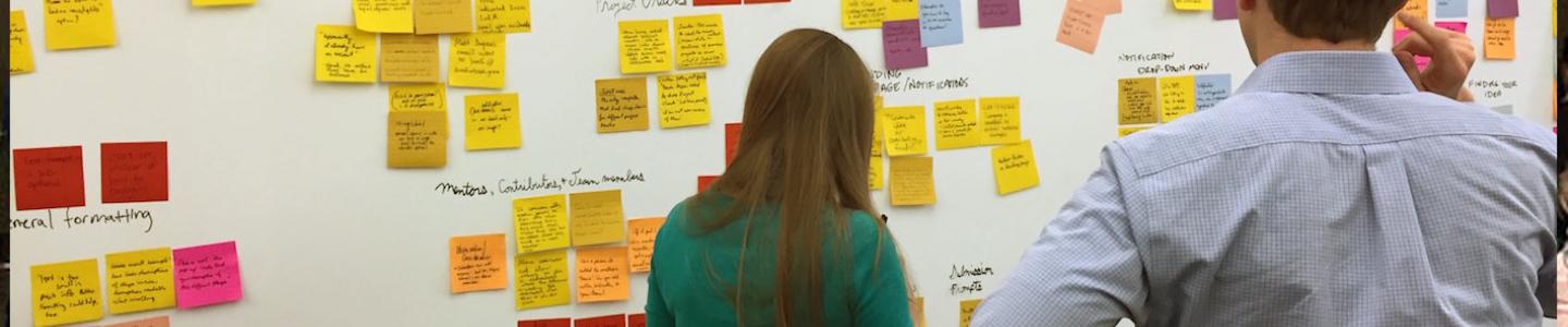 Innovation Office - people looking at sticky notes on a whiteboard