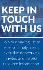 This image is a promotional vertical banner featuring the phrase "KEEP IN TOUCH WITH US" in bold, white uppercase letters at the top. Below the phrase, there's an invitation to "Join our mailing list to receive timely alerts, exclusive networking invites and helpful resource information." The background shows a blurred cityscape, emphasizing the professional context of the banner.