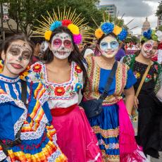 four ladies at the 2023 festival dressed in colorful costumes with painted faces and flower crowns