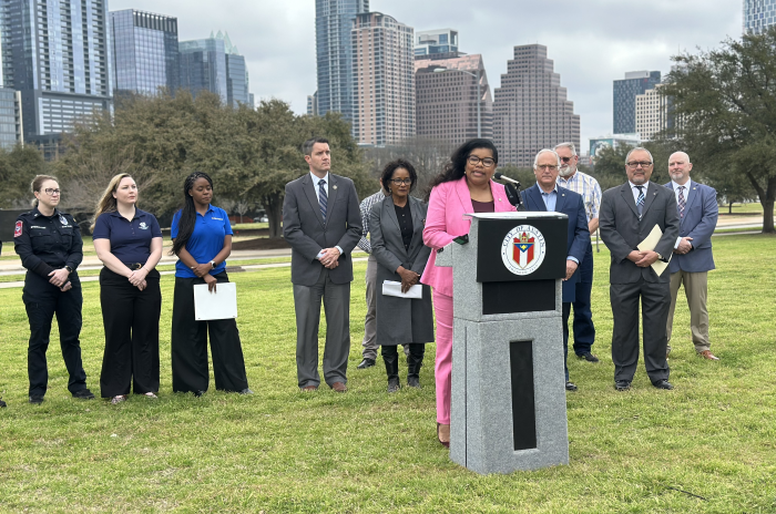 Press conference in park with city skyline in the background