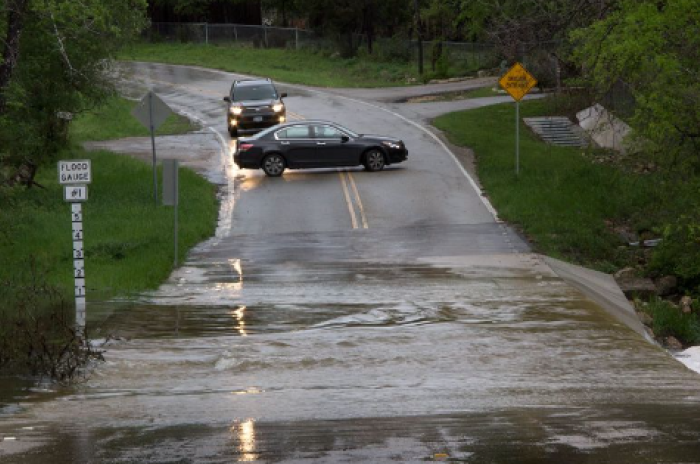 Two cars turn around to avoid a flooded roadway